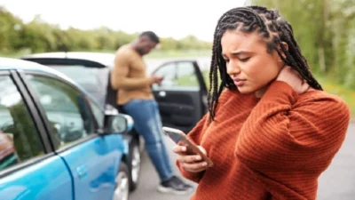 Car accident victim experiencing neck pain while documenting details at the accident scene in Las Vegas