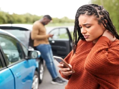 Car accident victim experiencing neck pain while documenting details at the accident scene in Las Vegas