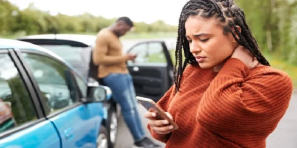 Car accident victim experiencing neck pain while documenting details at the accident scene in Las Vegas