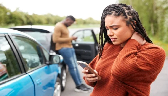Car accident victim experiencing neck pain while documenting details at the accident scene in Las Vegas